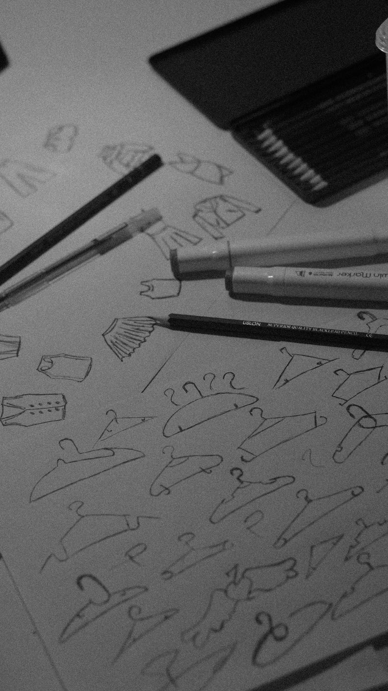 Sketches of clothes and hangers with pencils and pens.