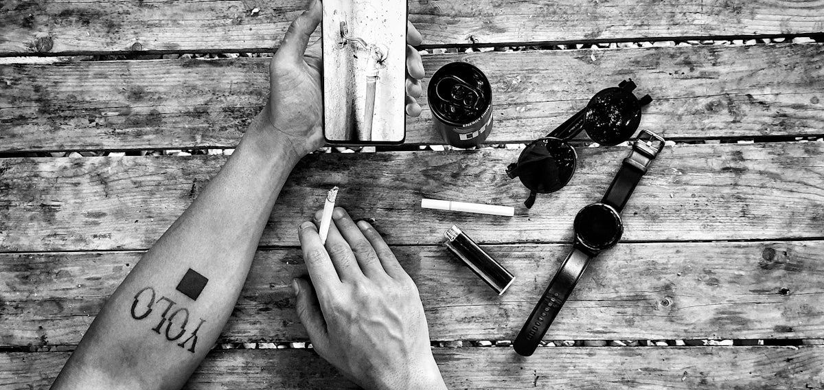 grayscale photo of person holding cigarette stick