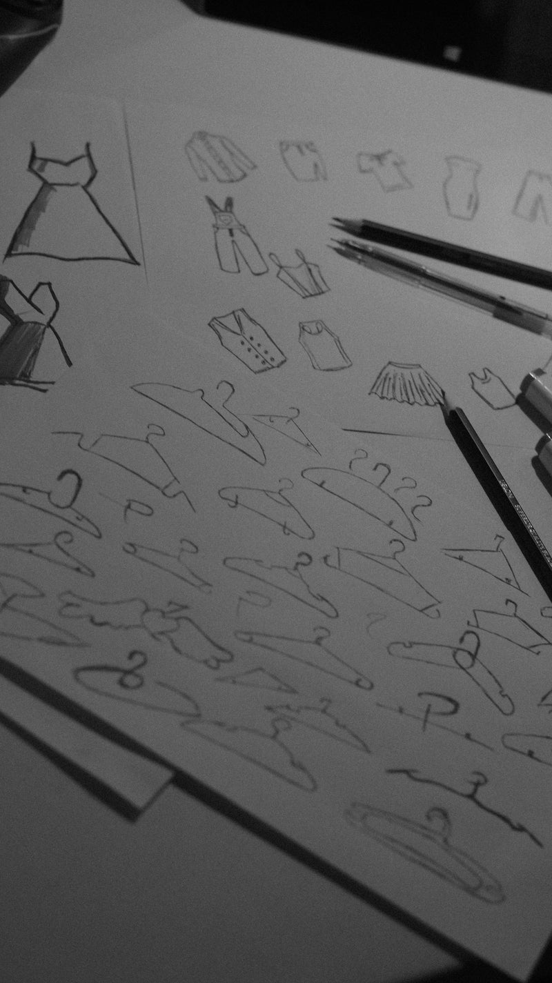 Sketches of clothing and hangers on paper.