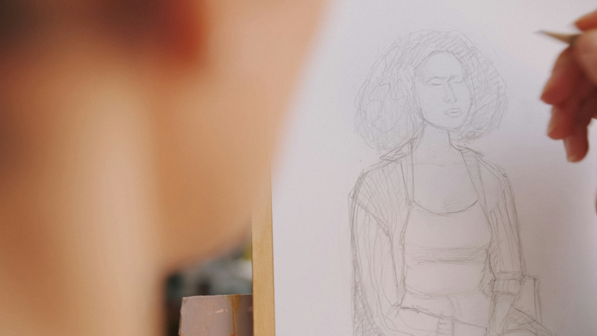 A person sketching a portrait of a woman with curly hair on paper