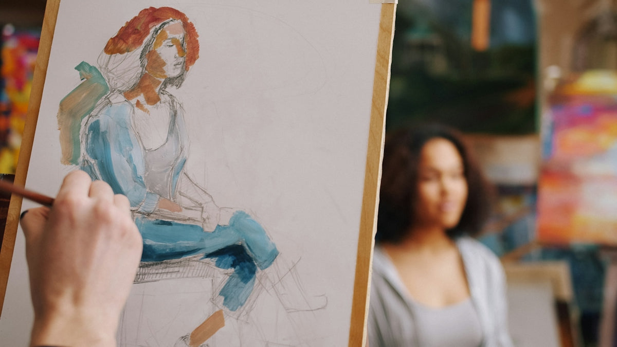 A person painting a portrait of a woman on a canvas in a studio